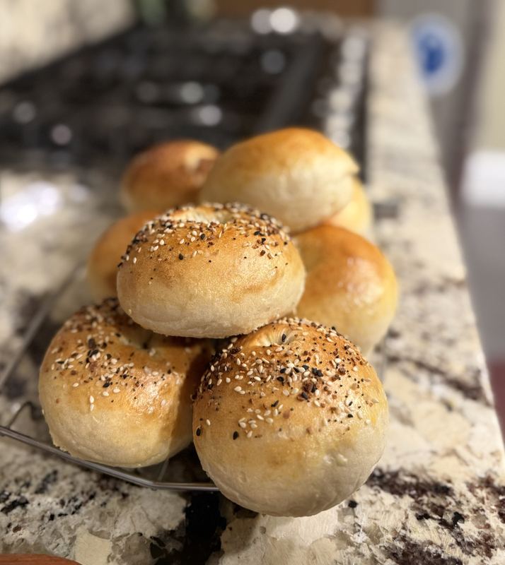 A stack of homemade bagels, some topped with everything seasoning