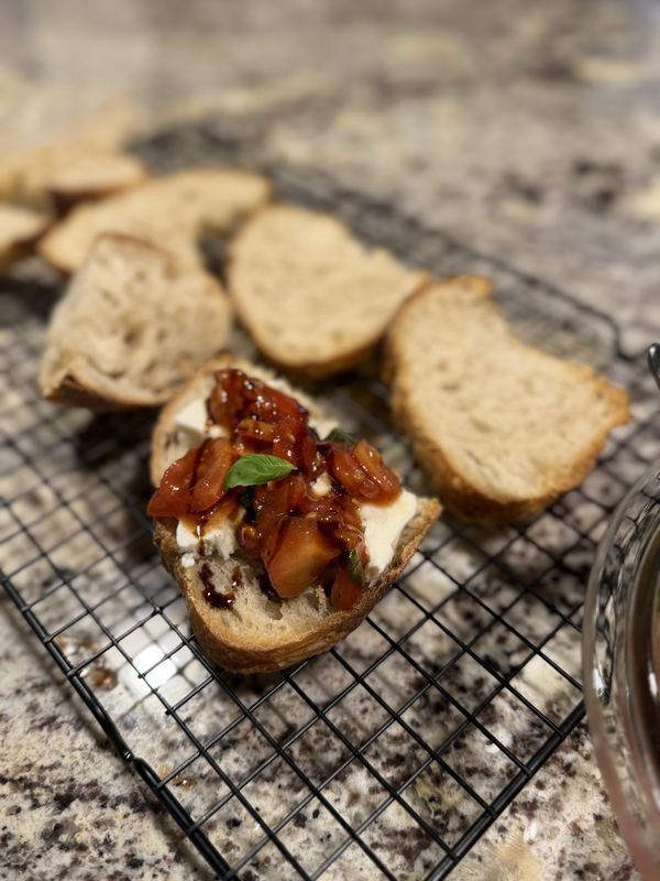 Slices of homemade bread, one topped with tomato, mozzarella, basil and balsamic