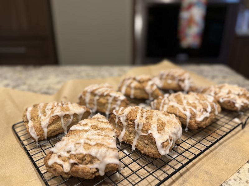 Cinnamon crumb scones with icing drizzle on a cooling rack