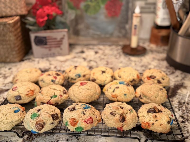 Thick, soft cookies full of colorful candy pieces cooling on a rack