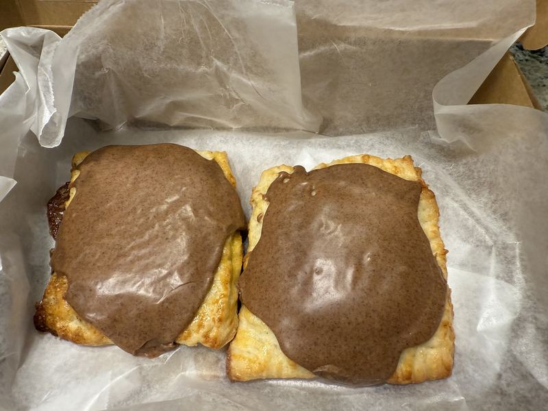 Two homemade frosted pastry tarts in a lined box