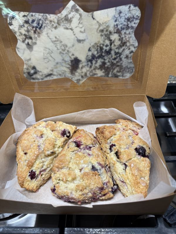 Glazed blueberry scones in a kraft bakery box with a window
